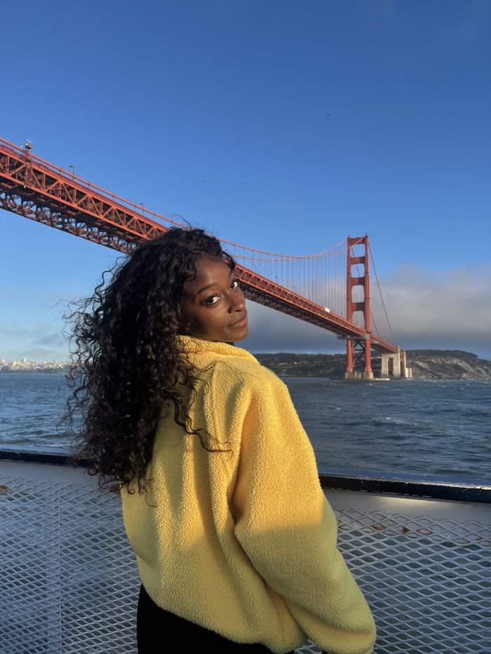 Faith Gowen in a yellow fleece, looking back over her shoulder on a boat beneath the Golden Gate Bridge