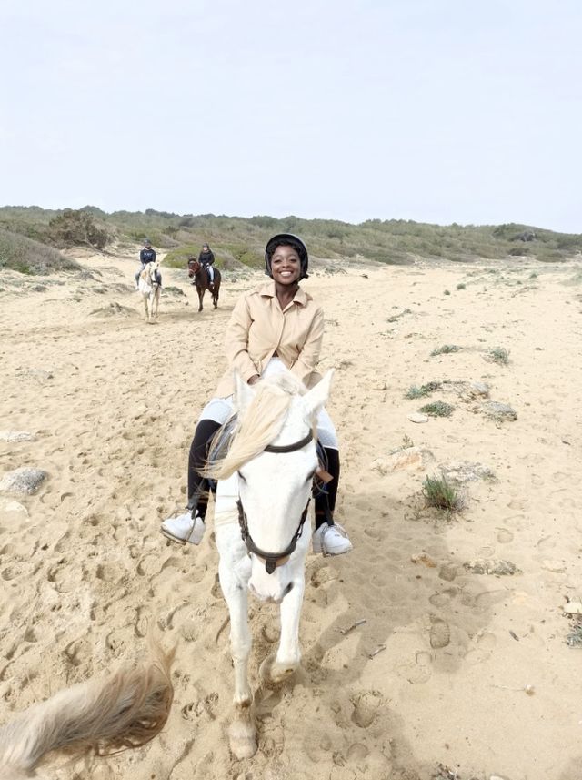 Faith riding a white horse on a sandy beach