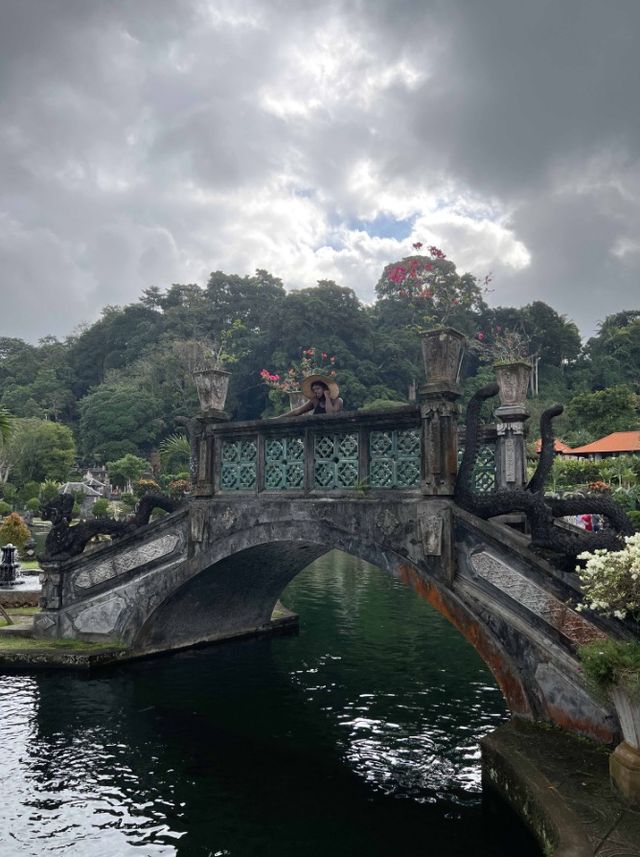 Faith on a carved stone bridge over dark water in a tropical water garden