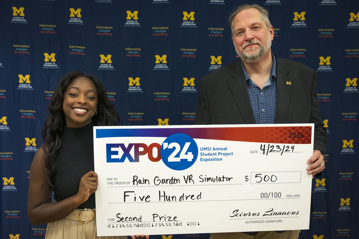 Faith Gowen holding the prize check for Rain Garden VR Simulator at the UMSI Student Project Exposition, April 2024
